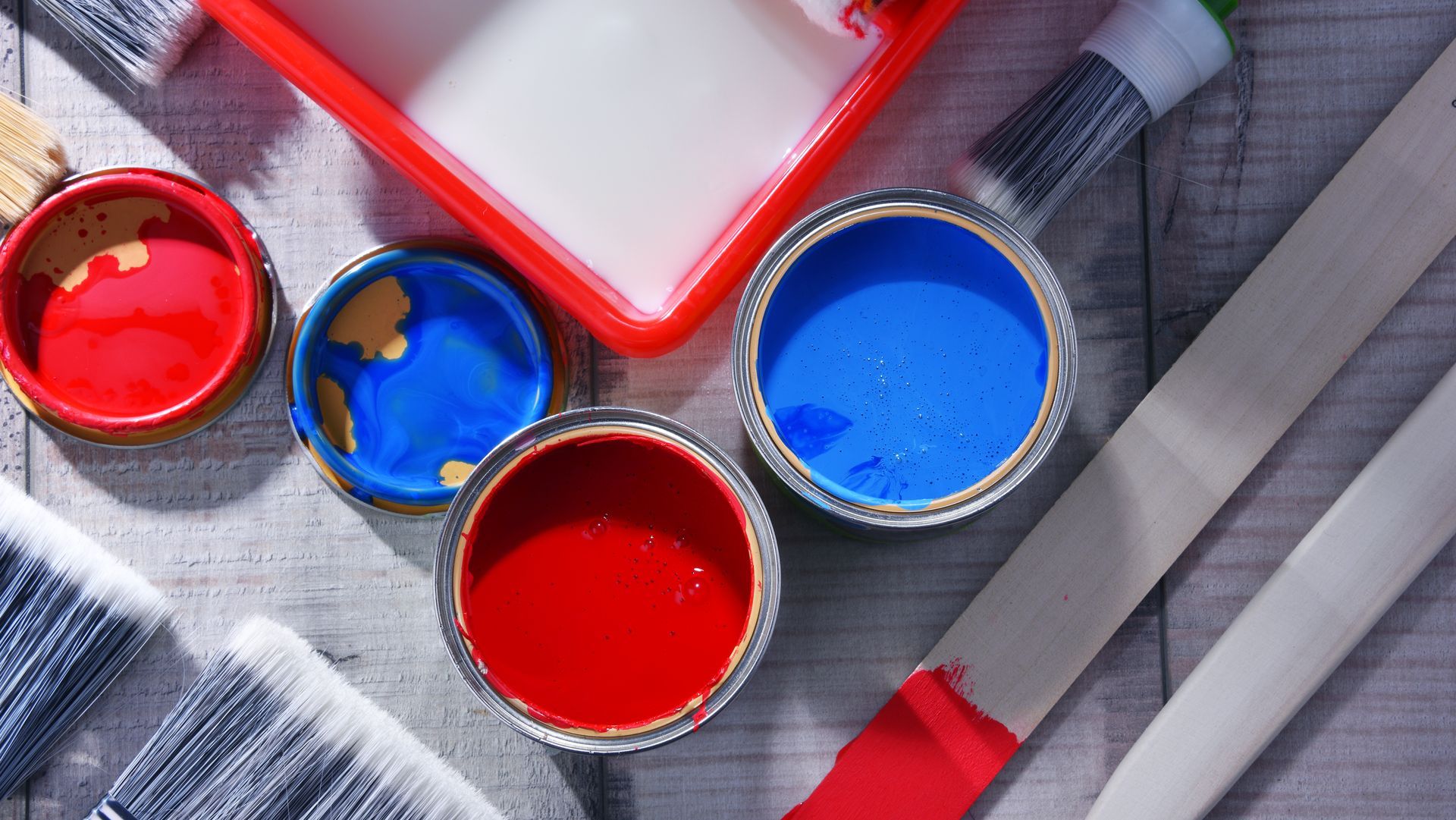 A bunch of paint cans and brushes on a wooden table.
