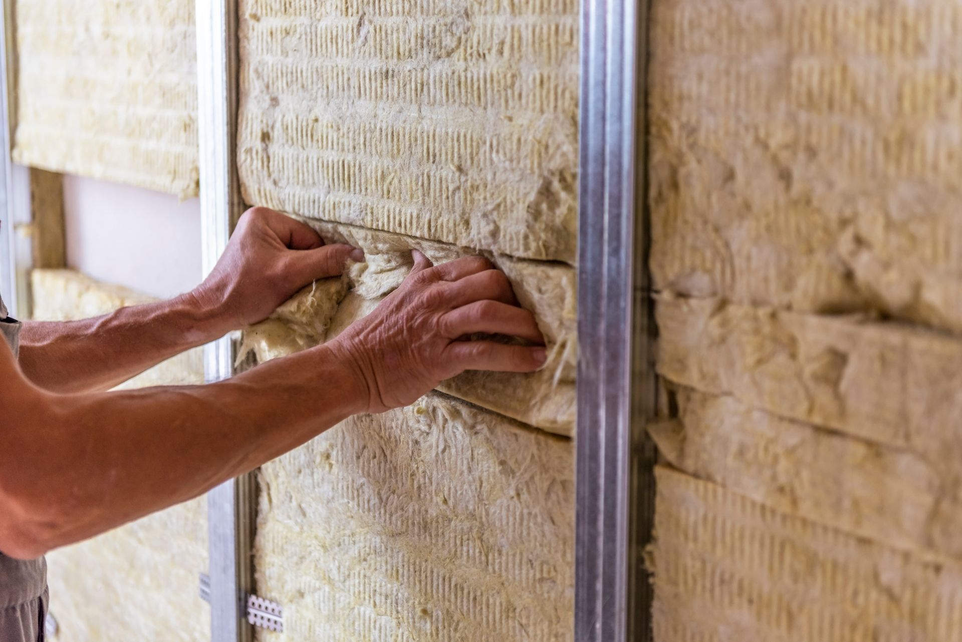 A man is installing rockwool insulation on a wall.