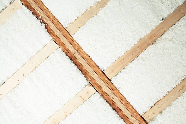 Insulated attic with wooden beams and white insulation material.