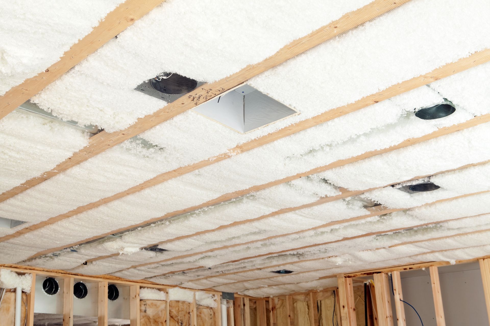 Ceiling with spray foam insulation and exposed wooden beams.