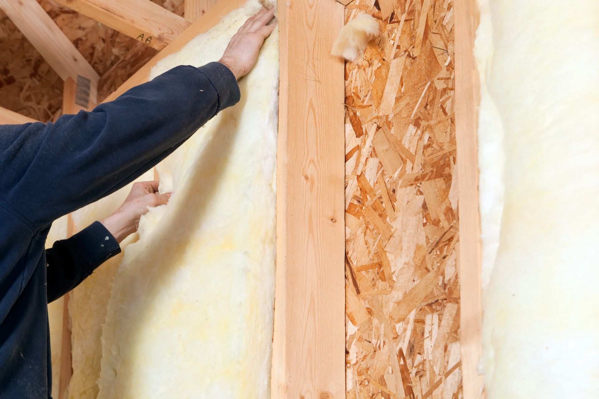 A man is applying insulation to a wooden wall.