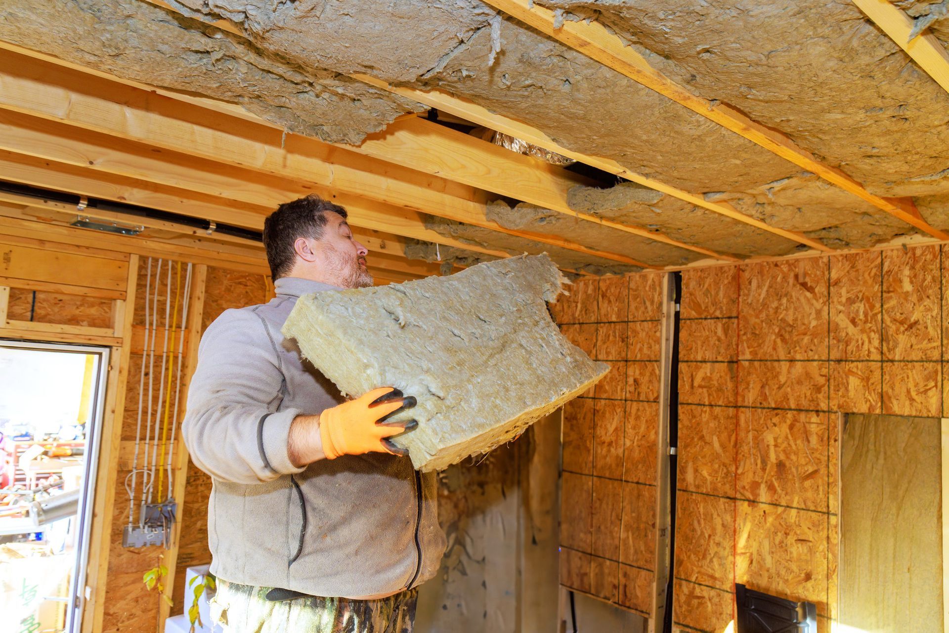 Construction worker installing insulation in a residential building. Construction worker installing insulation in a residential building.