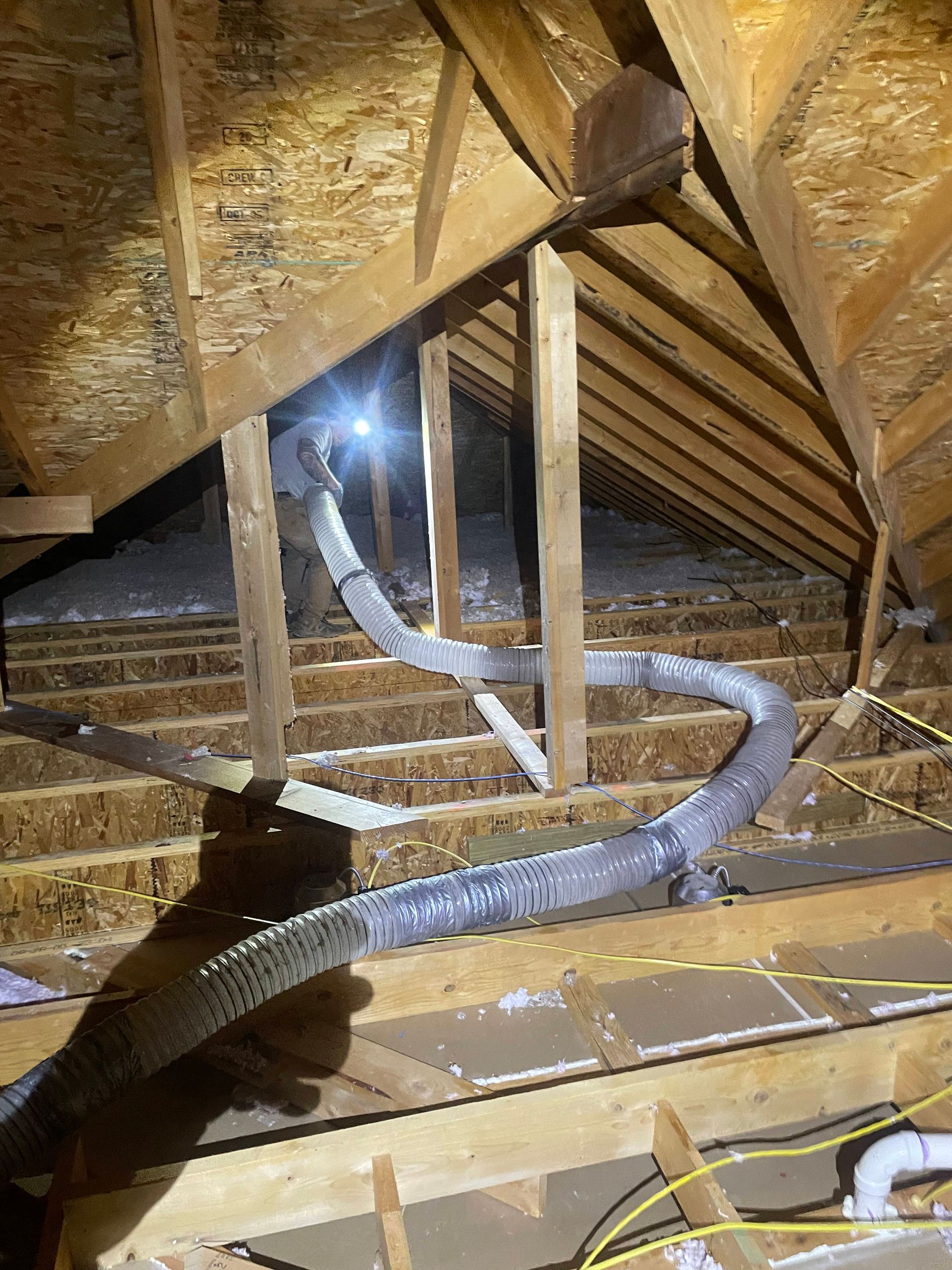 A hose is hanging from the ceiling of an attic.