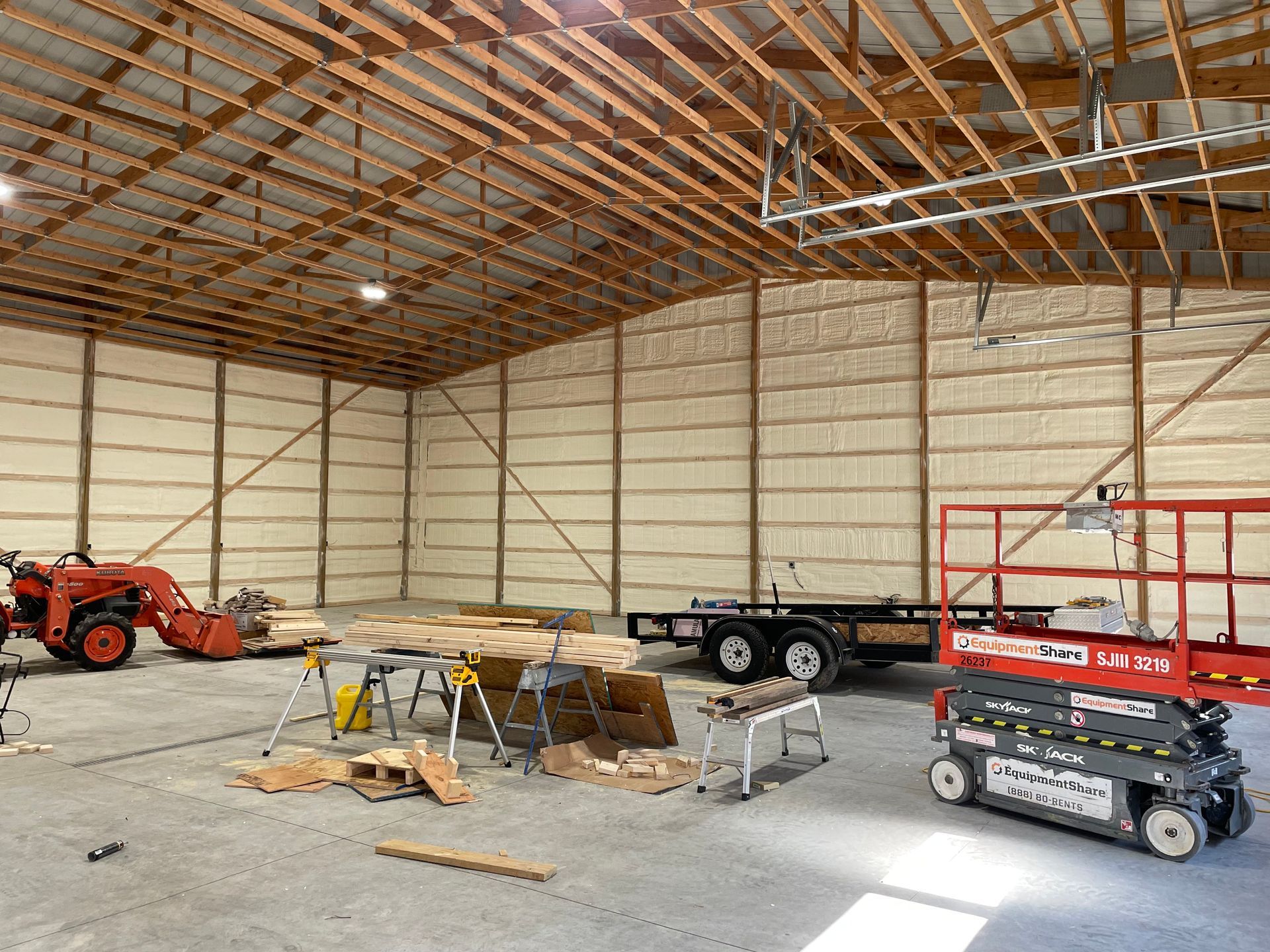 A large warehouse with a tractor and a scissor lift in it.