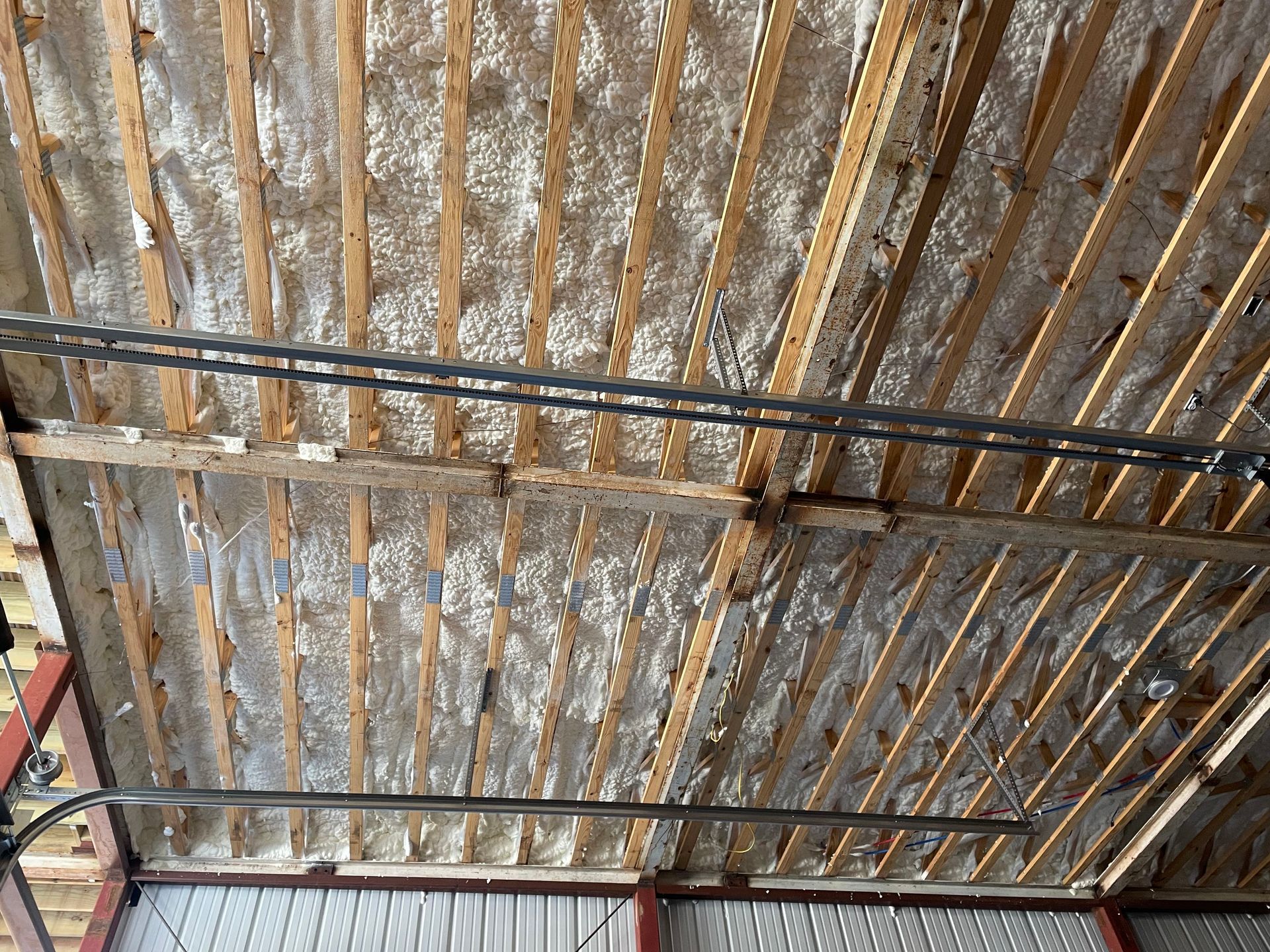 The ceiling of a garage is covered in foam and wooden beams.