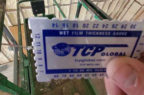 A person is holding a tcp global wet film thickness gauge