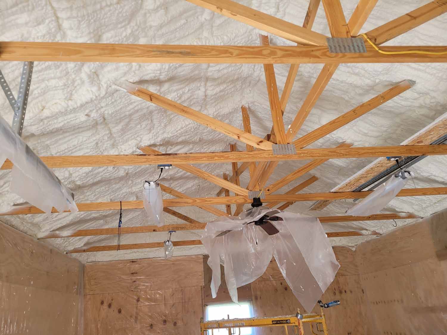 The ceiling of a building is covered in foam and there is a ceiling fan hanging from it.