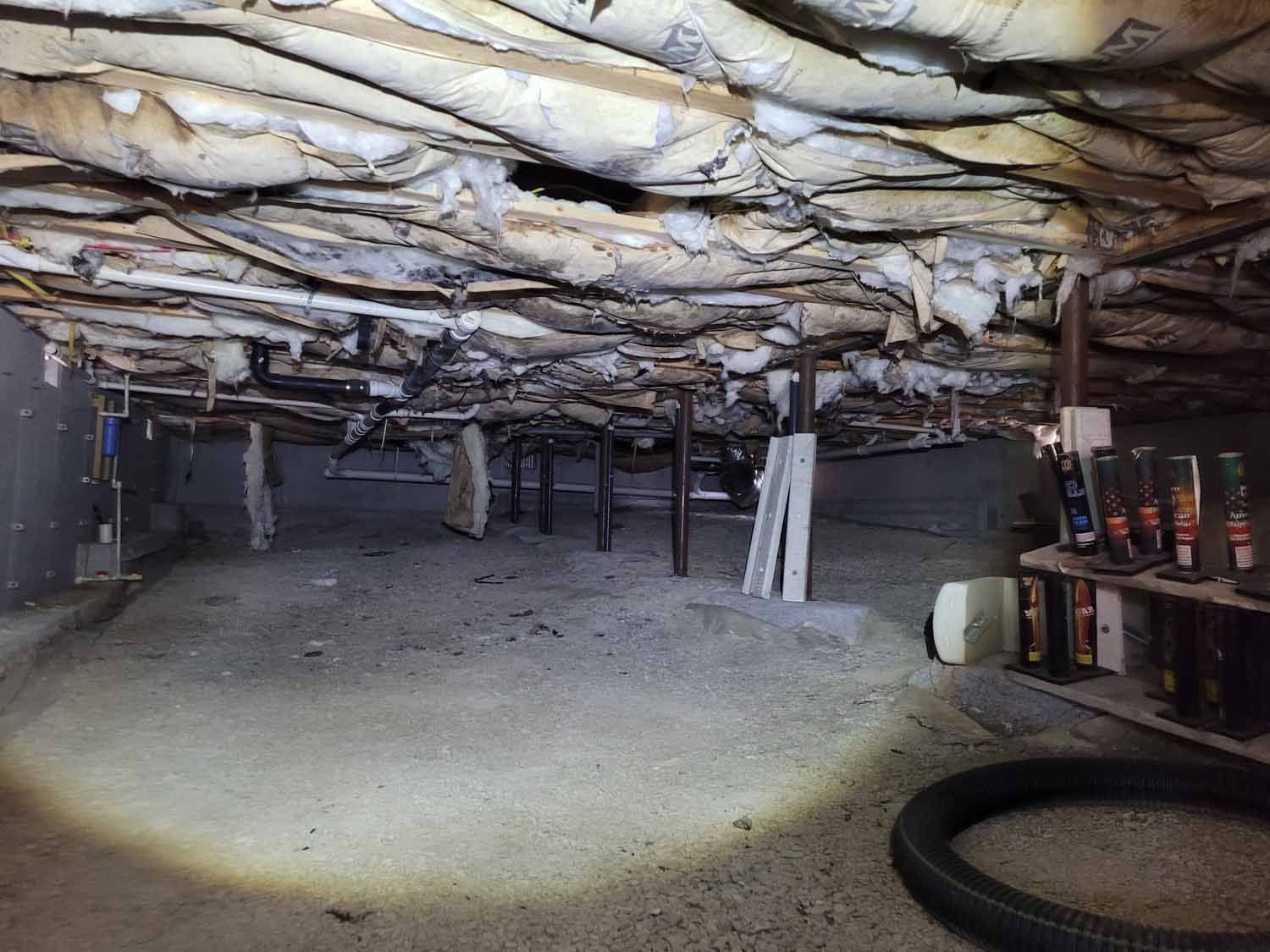 The ceiling of a basement with a lot of insulation and a vacuum cleaner.