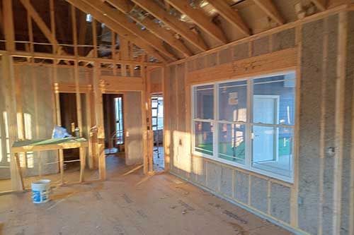 A room in a house under construction with a lot of windows.