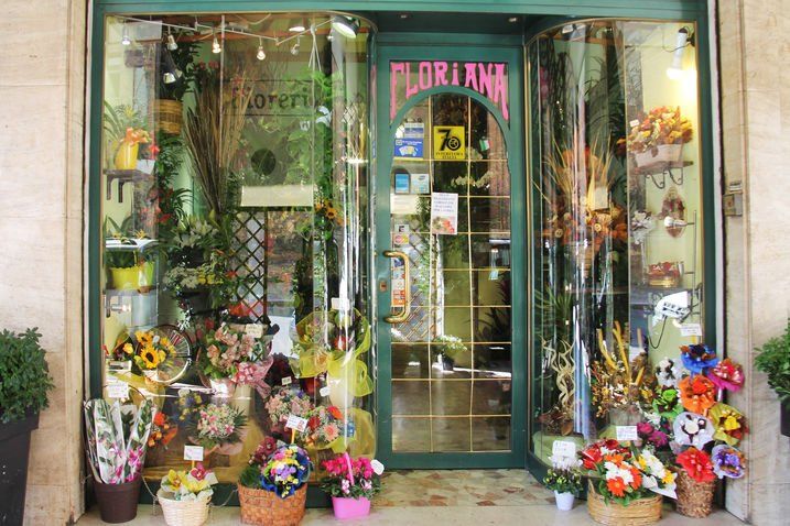 Vetrina del negozio di fiori Floriana con composizioni floreali colorate e accenti verdi.