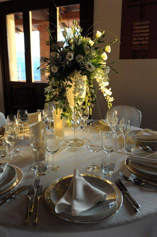 Elegante apparecchiatura da tavola con centrotavola di fiori bianchi. Apparecchiatura da pranzo formale con piatti, bicchieri e posate.