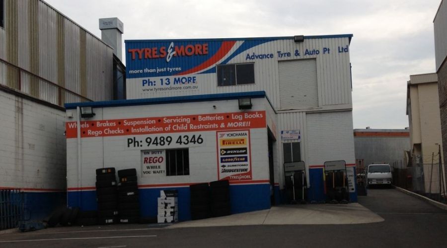 Tires & More auto shop in an industrial area, featuring a blue, white, and red exterior.