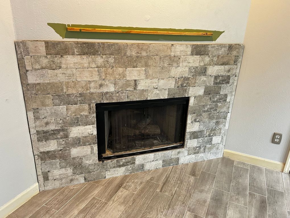Person kneeling, sanding wooden floorboards with a sanding block and wearing gloves.