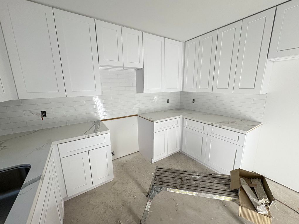 Modern bathroom with white tub, black fixtures, neutral-toned walls, and a large window.