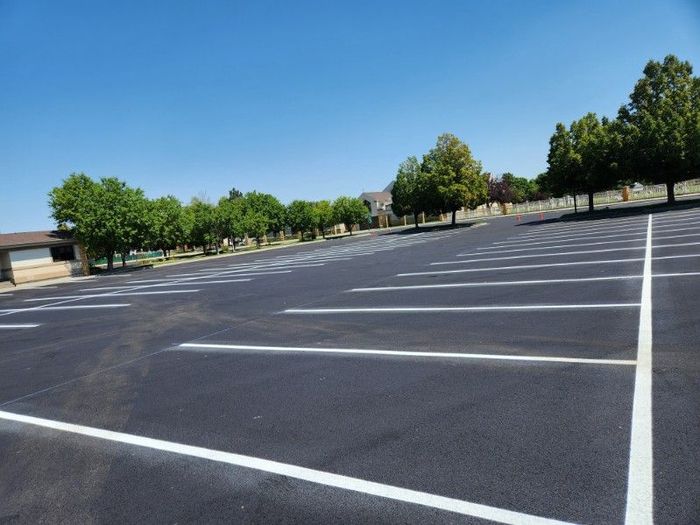 An empty parking lot with trees in the background