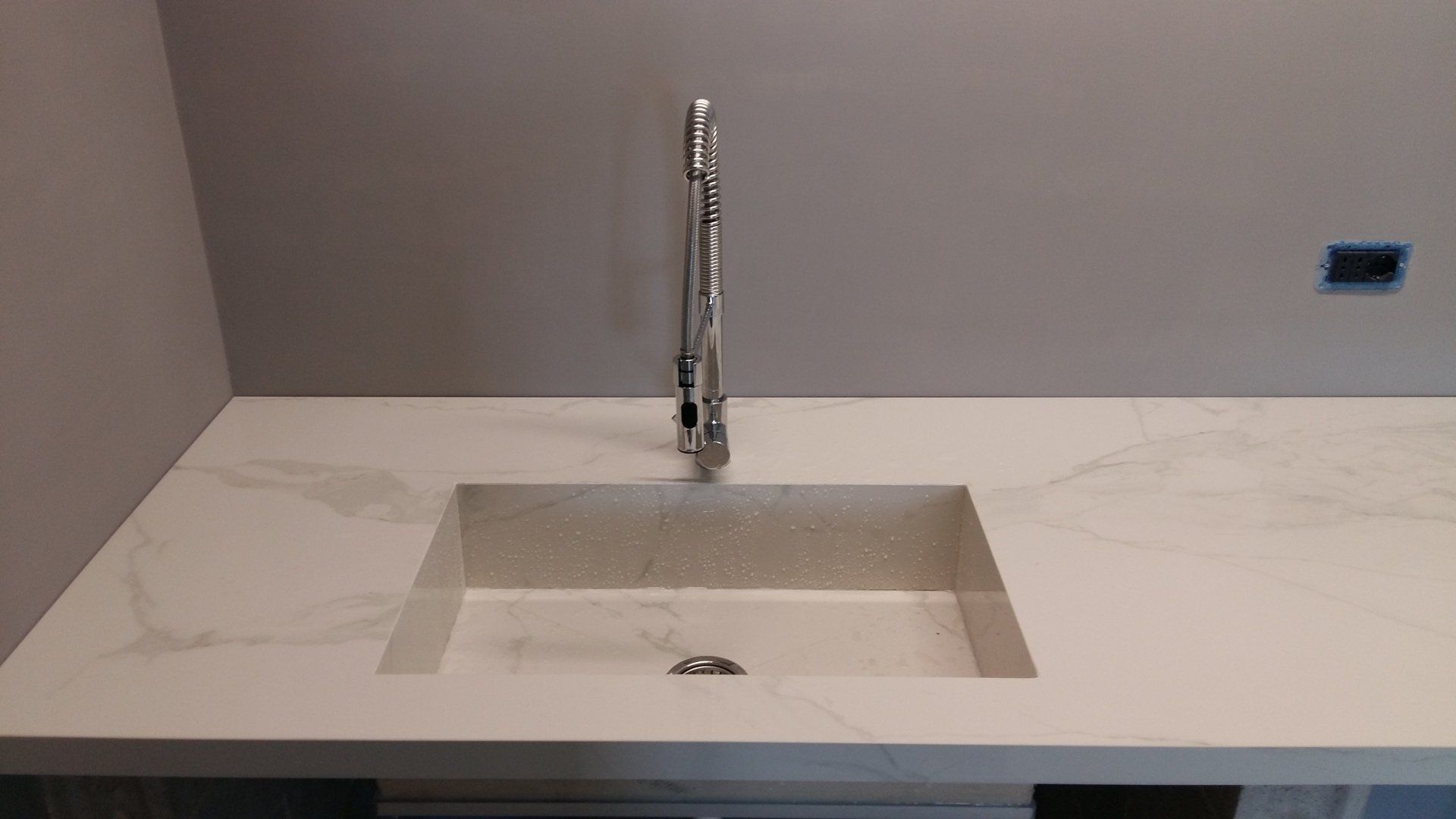 Un lavello da cucina con rubinetto su un piano di lavoro bianco.