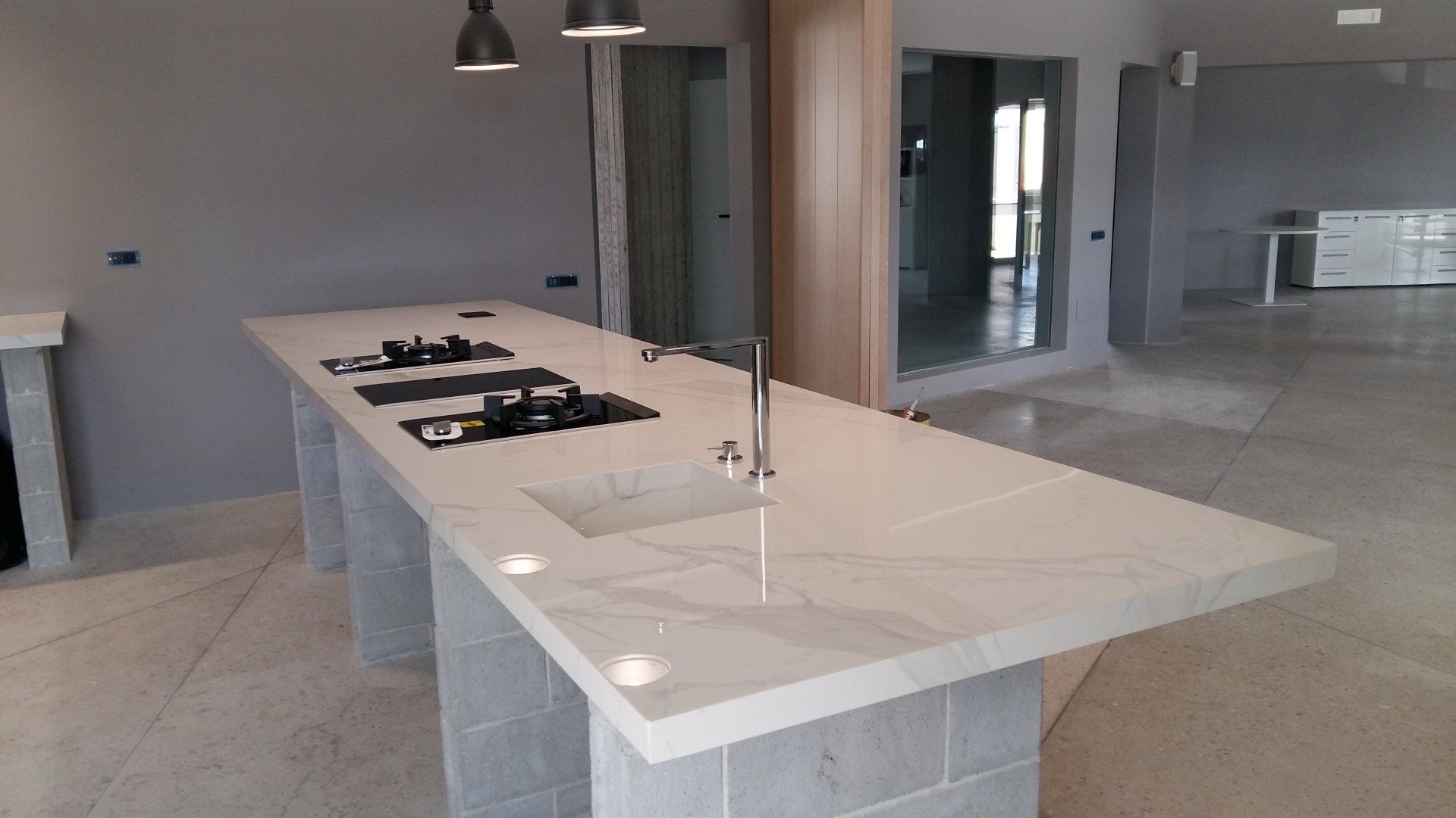 Una cucina con una grande isola con lavello, piano cottura e forno.