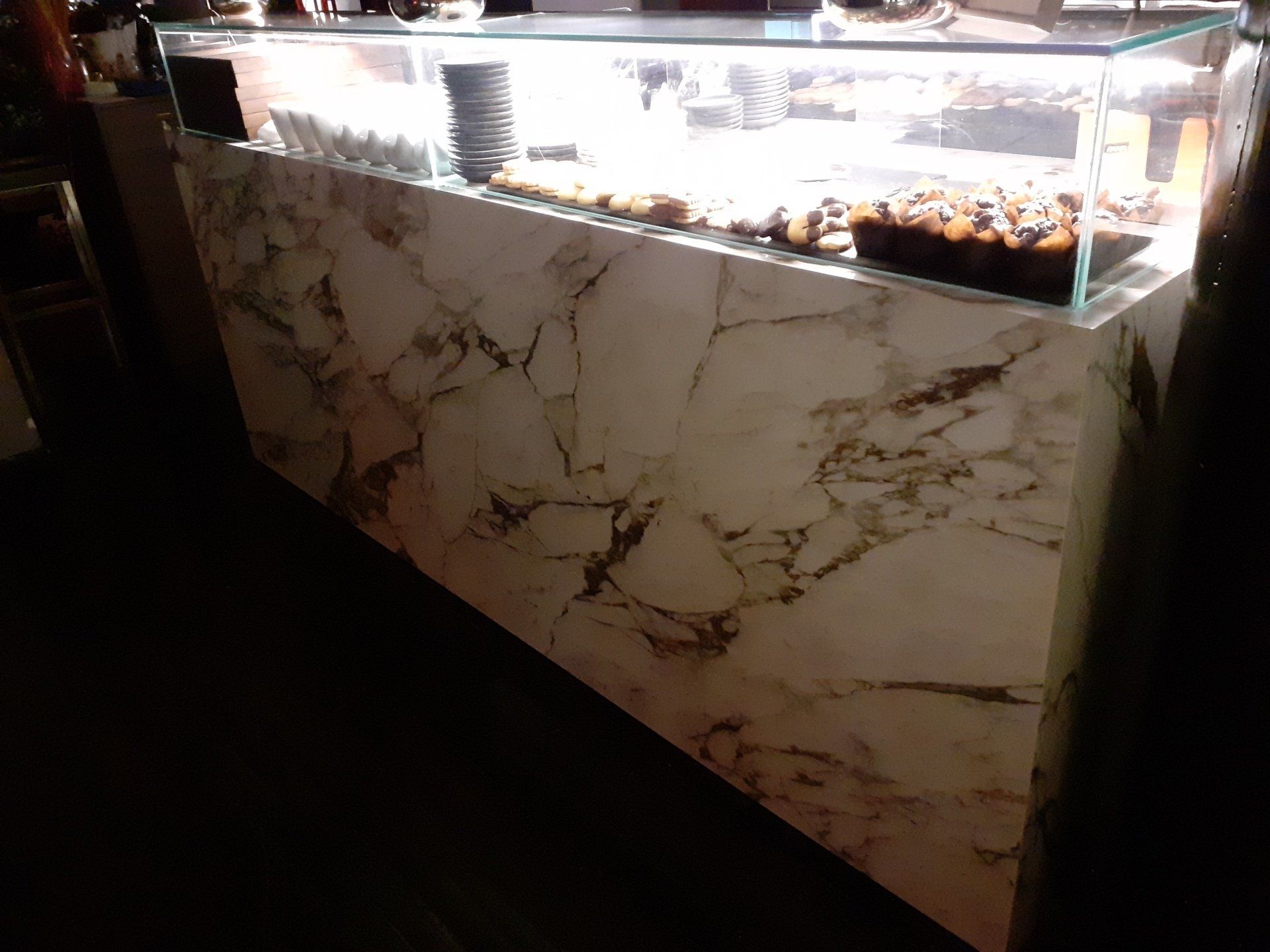 Un bancone in marmo con una vetrina in vetro piena di cibo.