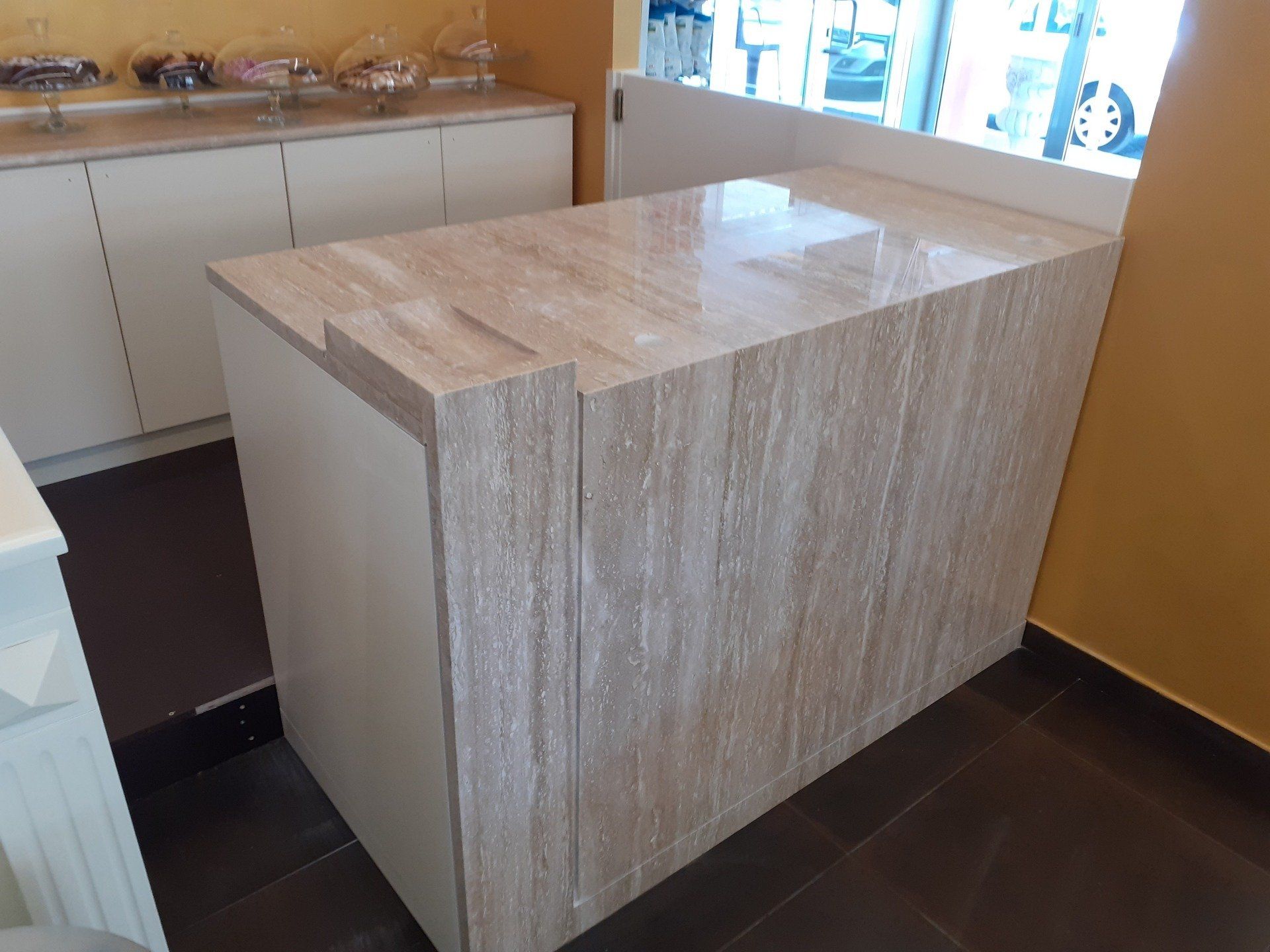 Una cucina con piano di lavoro in marmo e mobili bianchi.