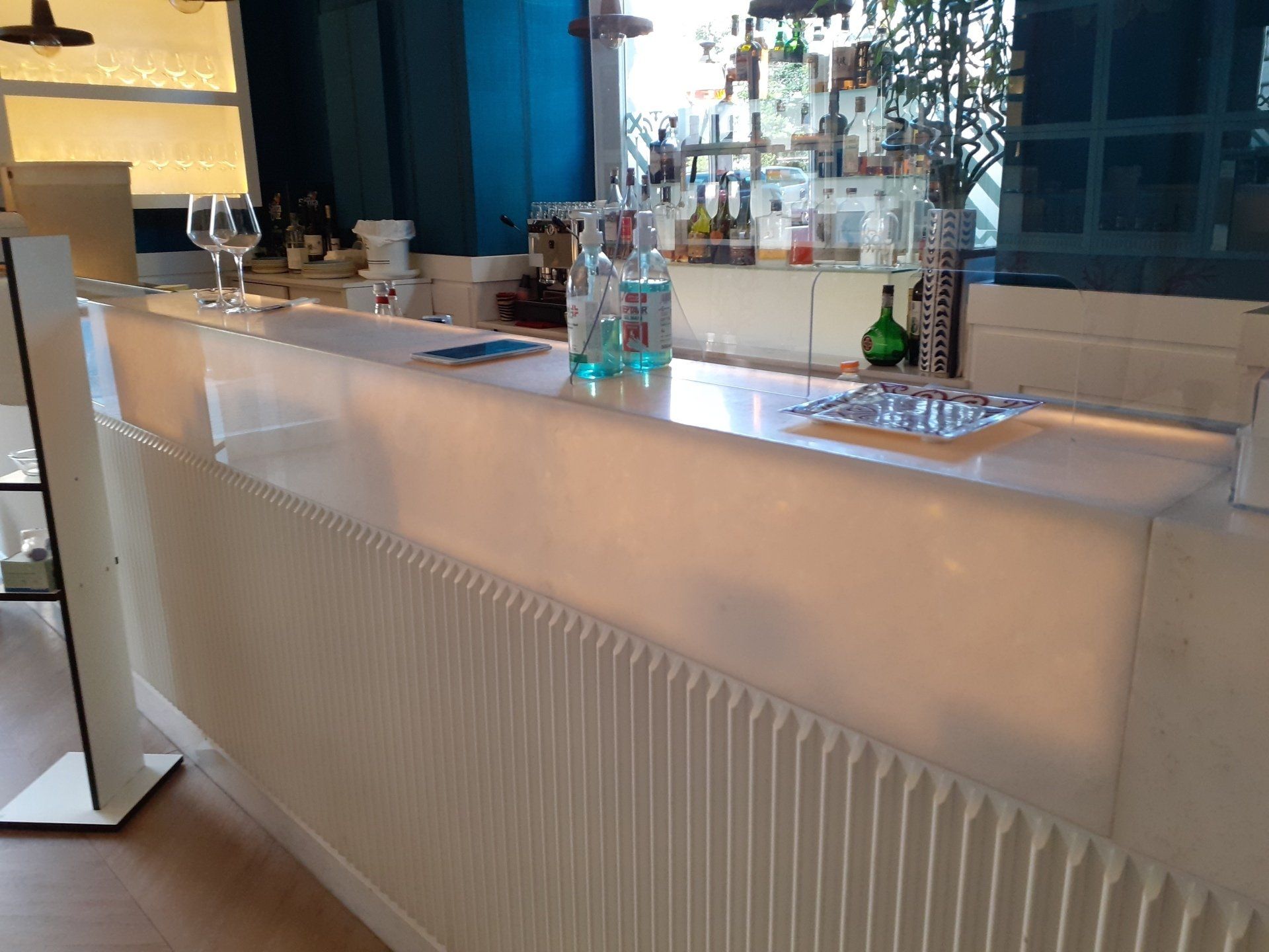 Un lungo bancone bianco con bottiglie e bicchieri sopra