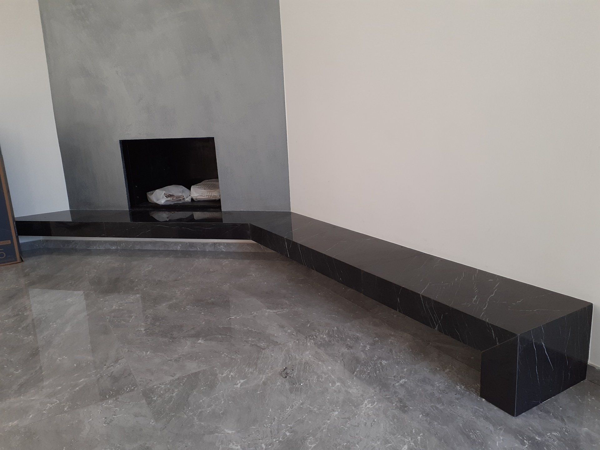 Una panca nera è posizionata davanti al camino in un soggiorno.