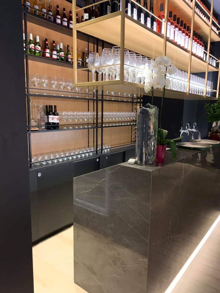 Un bar con un sacco di bottiglie di vino e bicchieri sugli scaffali.