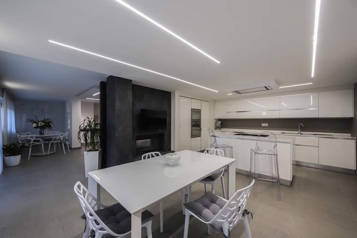 Una sala da pranzo con tavolo e sedie e una cucina sullo sfondo.