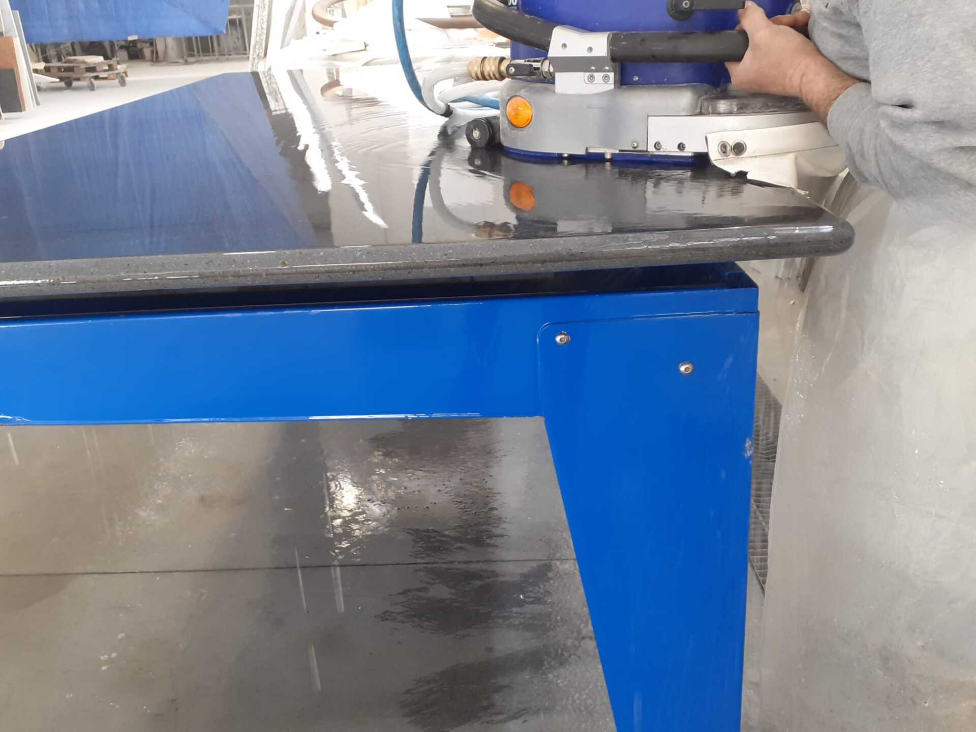 Un uomo sta usando una macchina per tagliare un pezzo di granito.