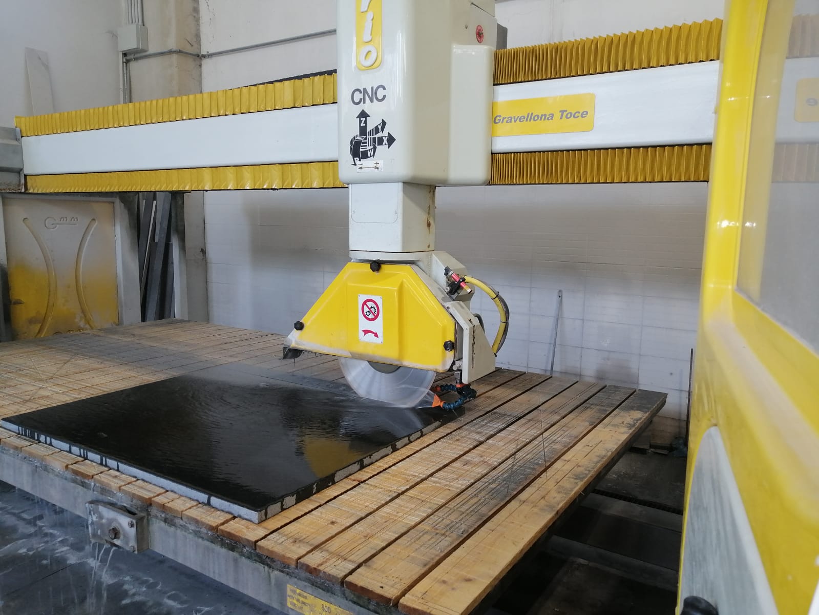 Una macchina gialla e bianca sta tagliando un pezzo di legno.