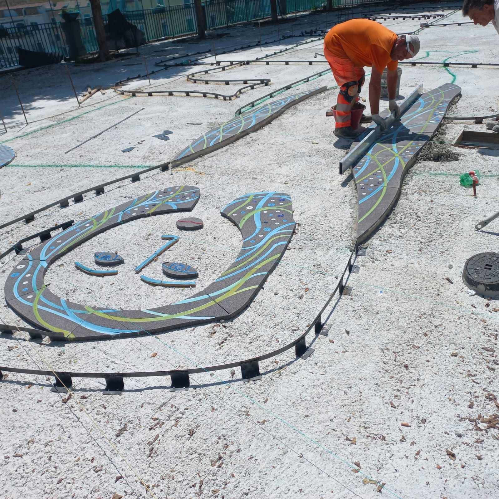 Un uomo con pantaloni arancioni sta lavorando a un dipinto a terra