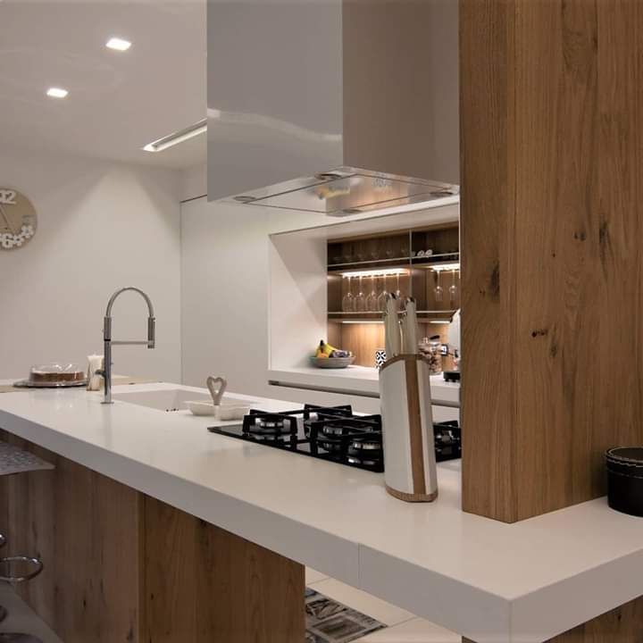 Una cucina con piano cottura, forno, lavello e un orologio a parete.