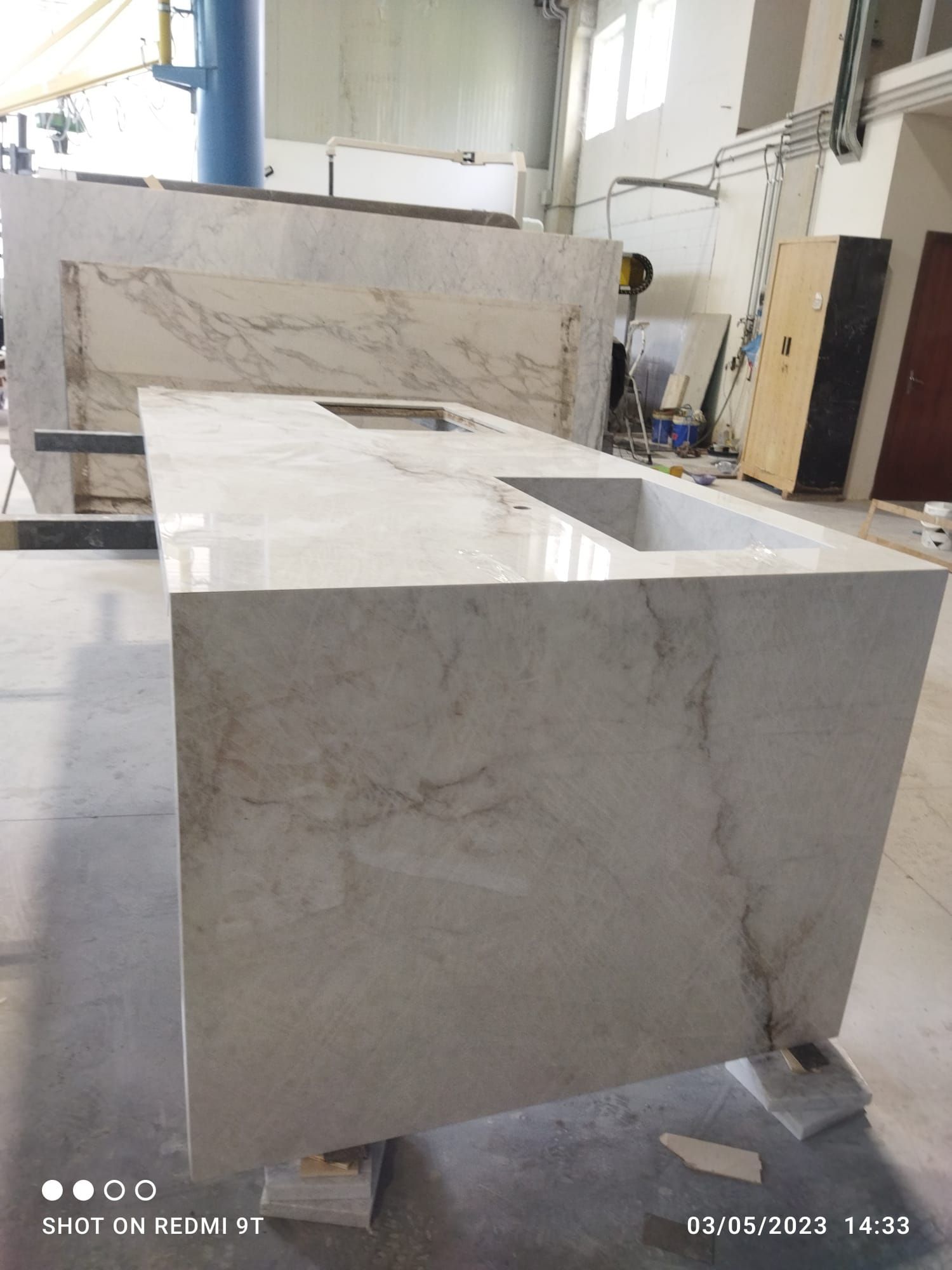 Un piano di lavoro in marmo bianco con un lavandino in una fabbrica.