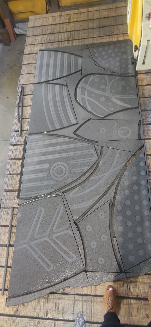 Una persona è in piedi accanto a un pezzo di metallo su un tavolo di legno.