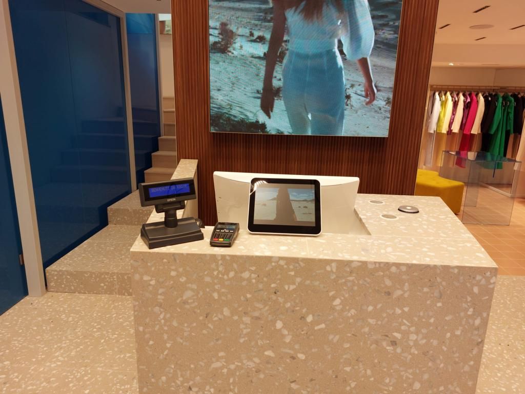 Una donna cammina sulla spiaggia su uno schermo sopra il bancone di un negozio.