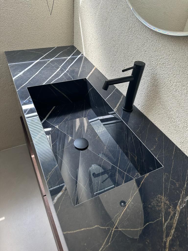 Un lavandino del bagno con un rubinetto nero e uno specchio.