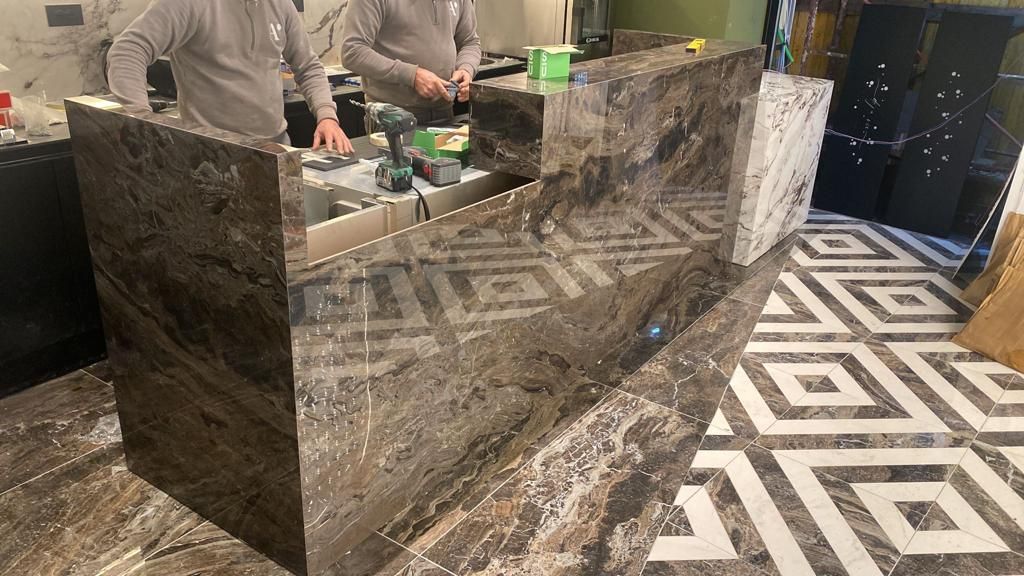 Due uomini stanno lavorando su un piano di marmo in una cucina.