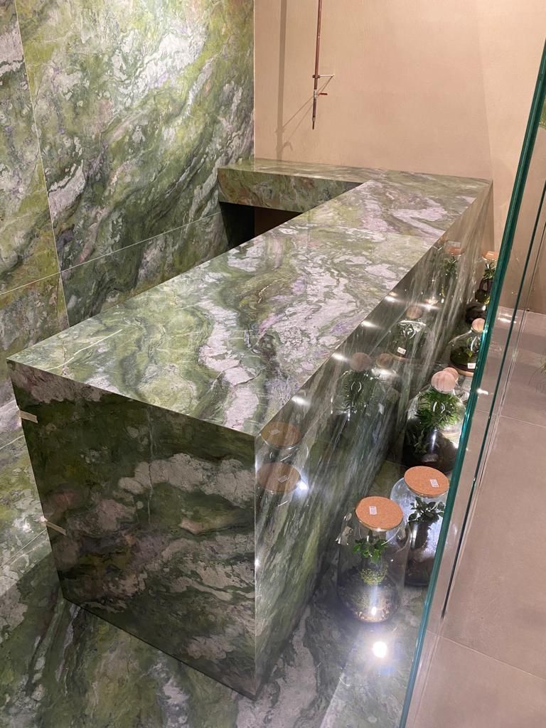 Un bagno con un piano in marmo verde e sgabelli.