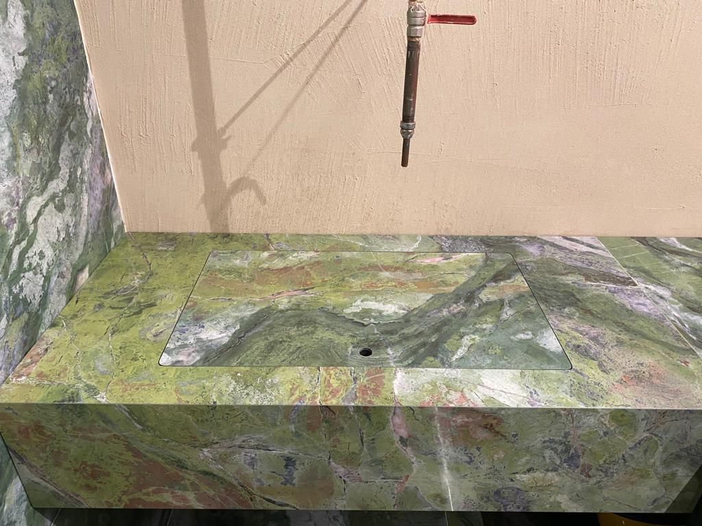 Un lavandino in marmo verde con un rubinetto attaccato.