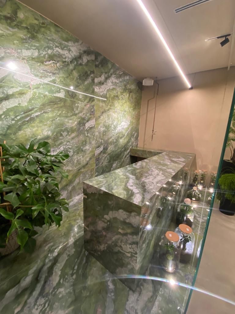 Un bagno con un piano di lavoro in marmo verde e una parete verde.