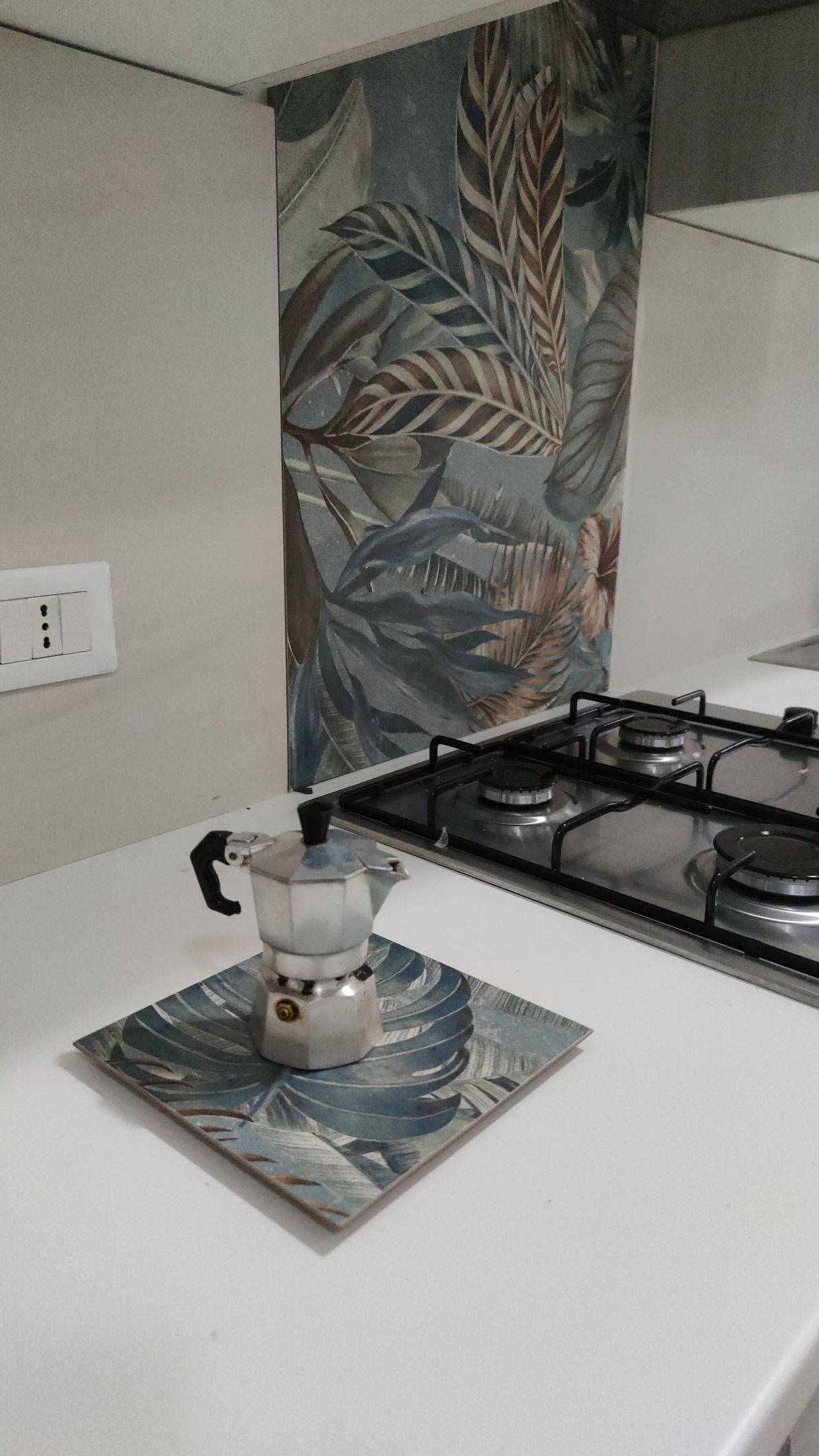 Una caffettiera è appoggiata su un tavolo accanto ai fornelli.