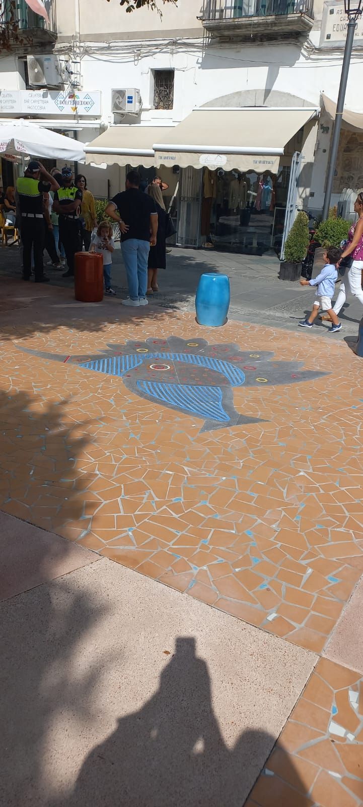 Un gruppo di persone è in piedi in una piazza di fronte a un edificio.