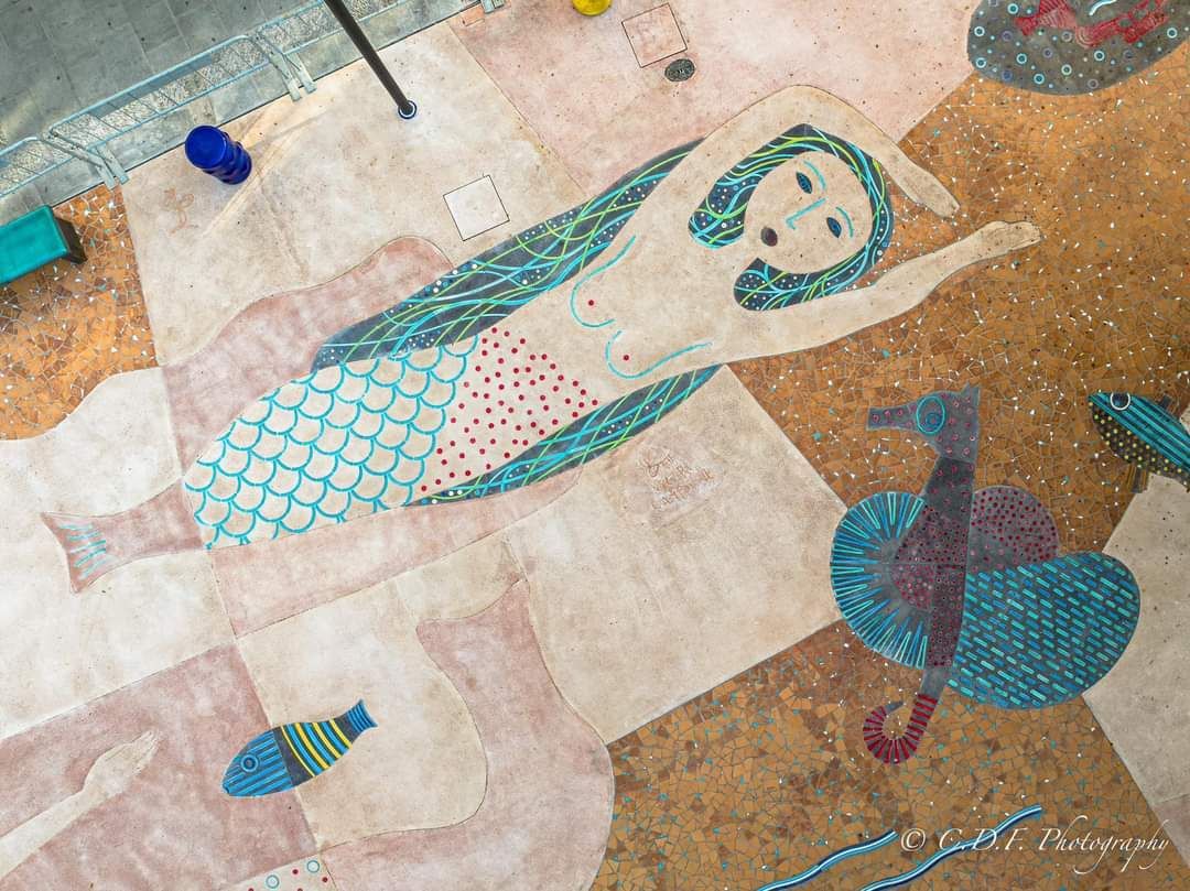 Un dipinto di una sirena e di un cavalluccio marino sul pavimento.