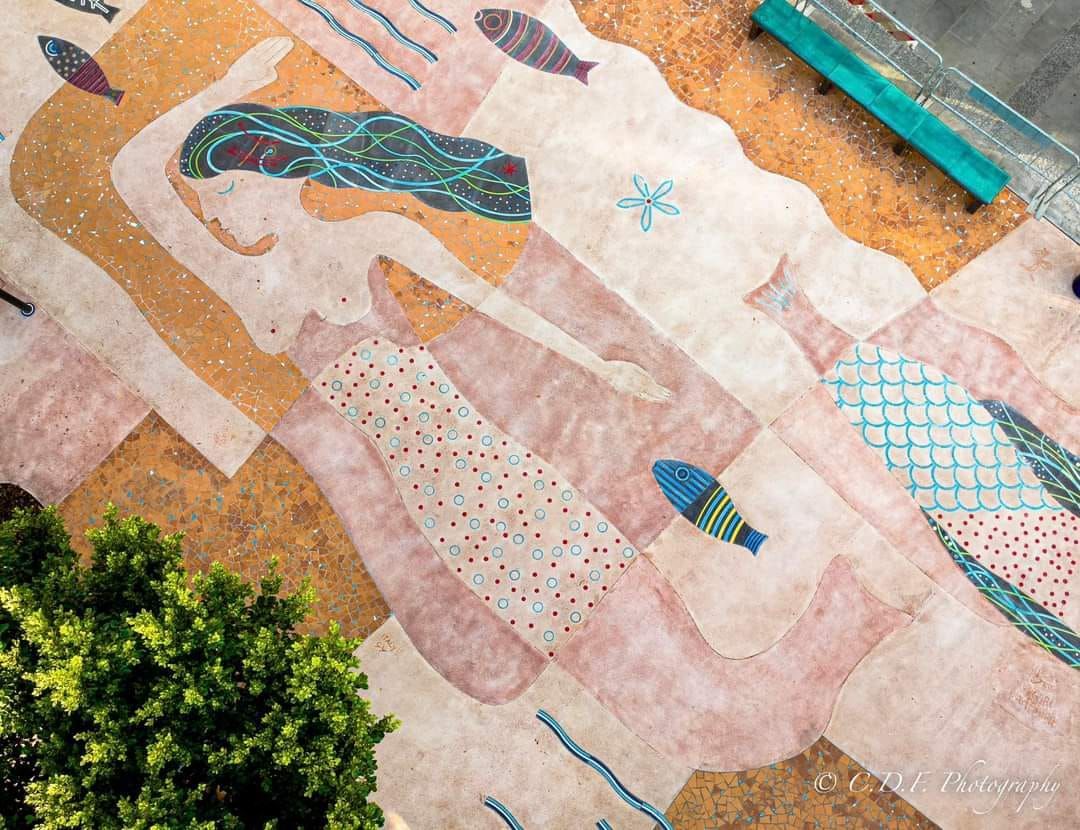 Un dipinto di una donna e un pesce su un muro