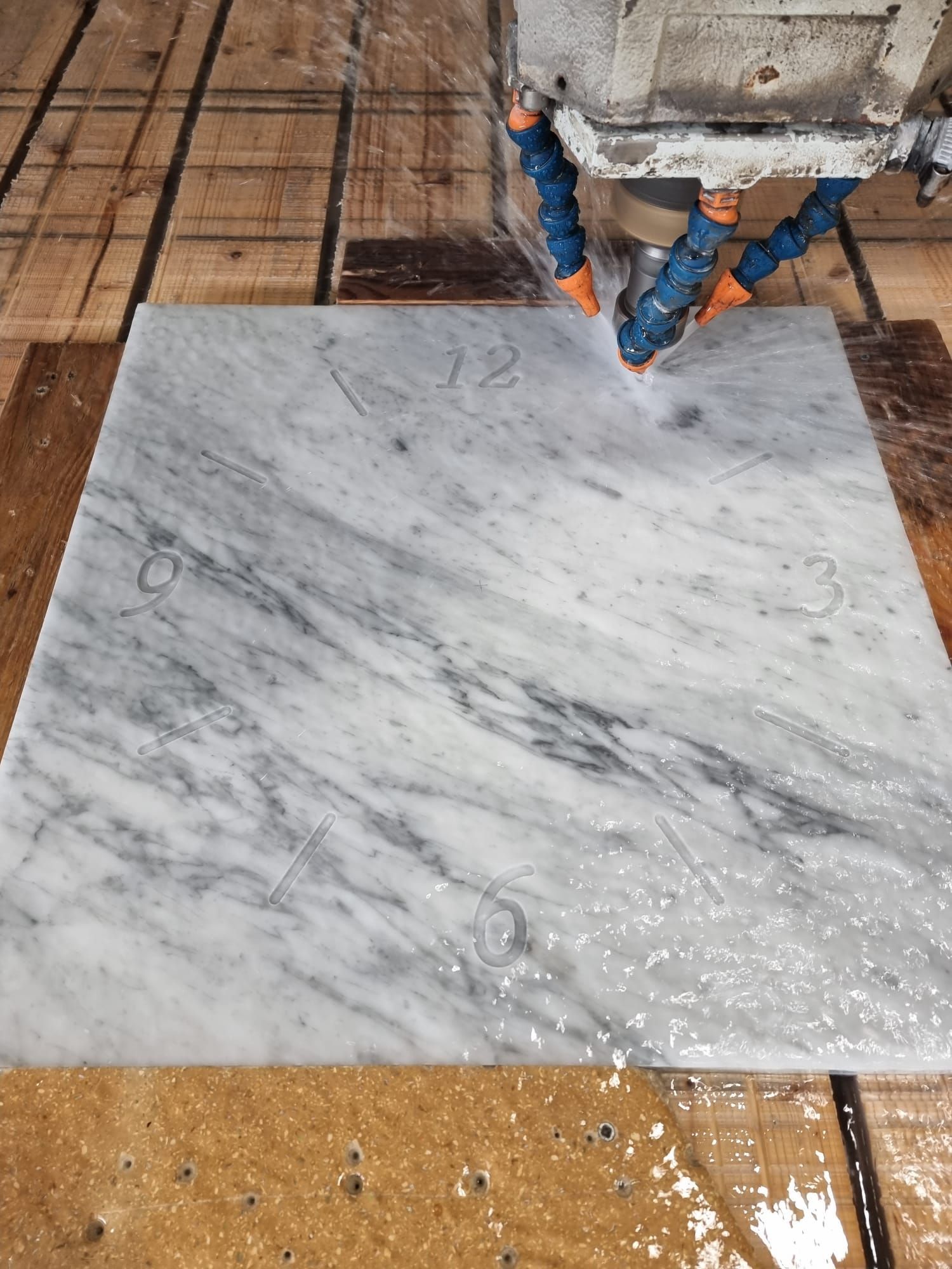 Una macchina sta tagliando un pezzo di marmo su un tavolo di legno.