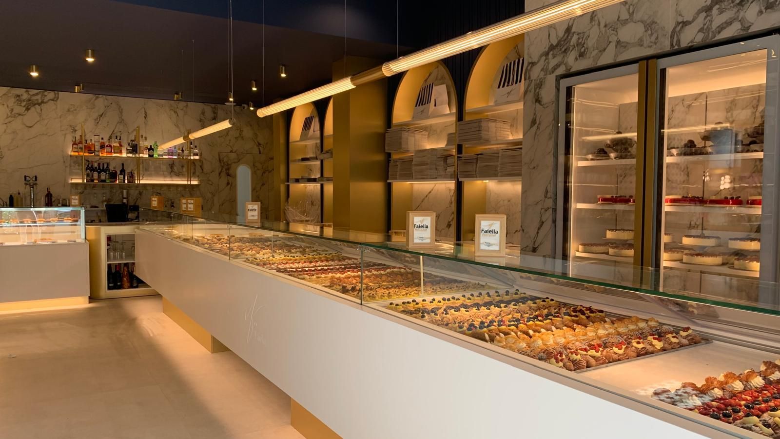 Un panificio con un lungo bancone pieno di cibo.