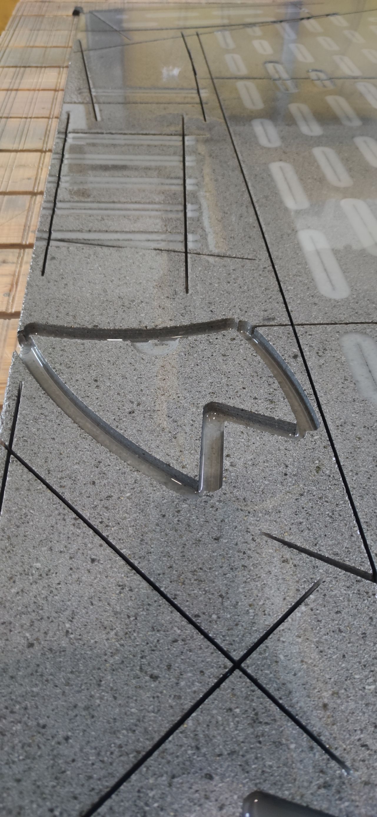 Un pavimento di piastrelle grigie con un pezzo di metallo rotto sopra.
