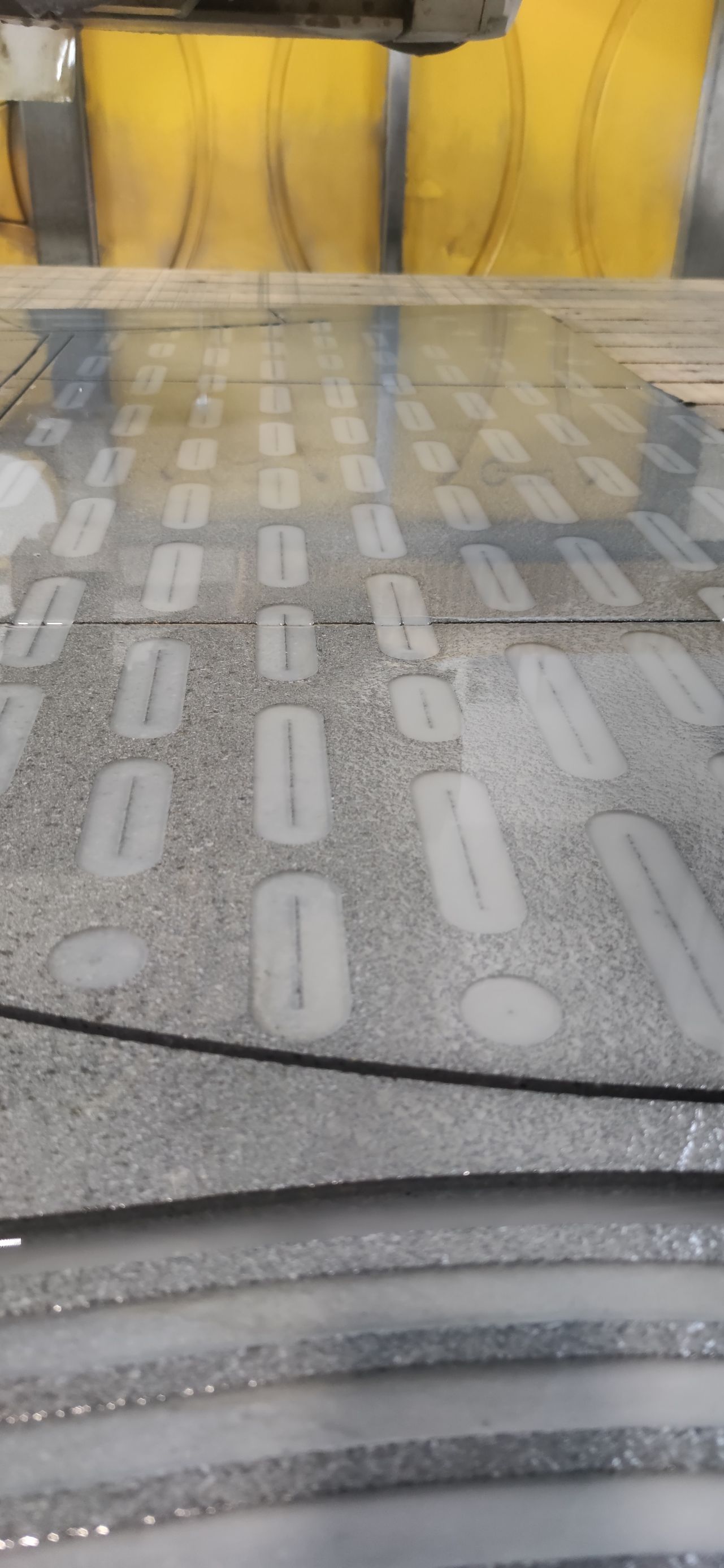 Un primo piano di un tavolo di vetro con un divano giallo sullo sfondo.