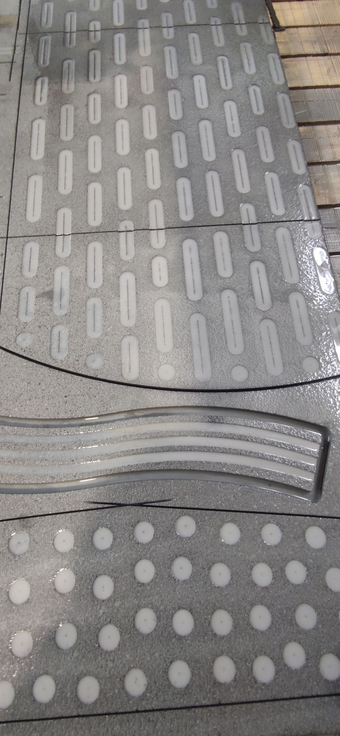 Un primo piano di un pavimento in piastrelle grigie con dei puntini bianchi.