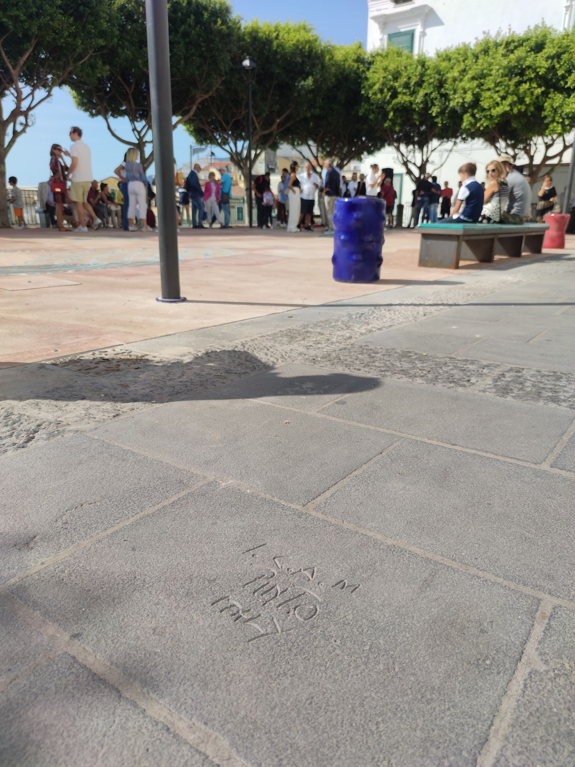 Un gruppo di persone è riunito in un parco con un barile blu in primo piano
