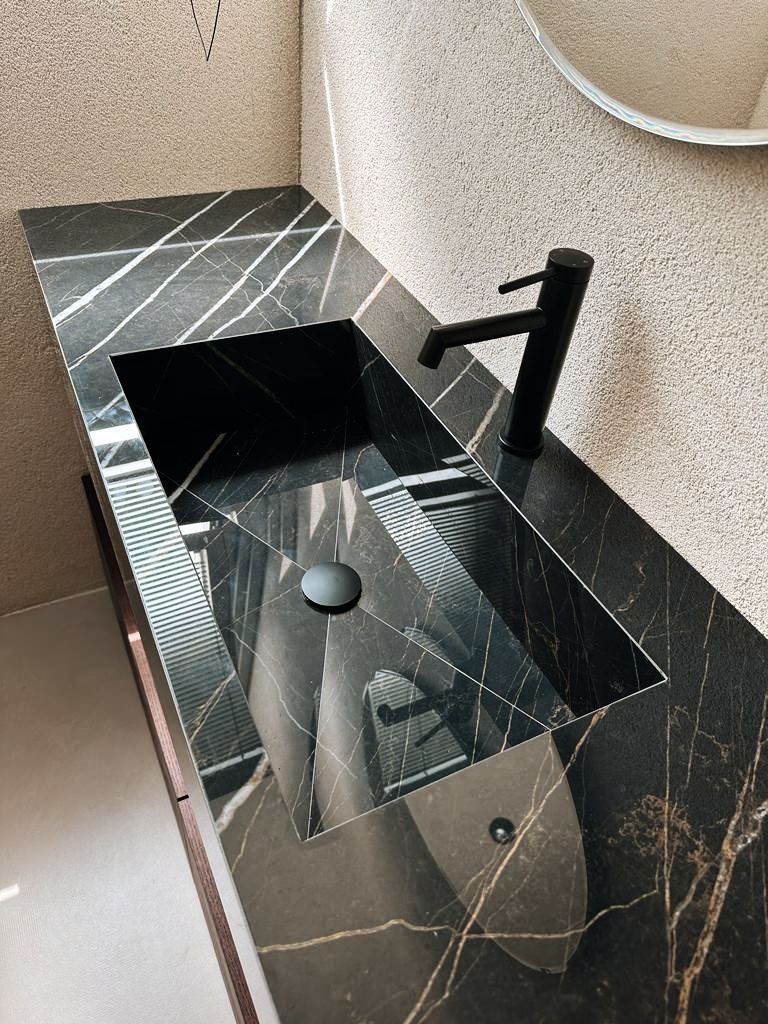Un lavandino del bagno con un rubinetto nero e uno specchio.